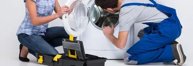 Washer repair technician inspecting a front-load washing machine with tools in Clearwater, FL
