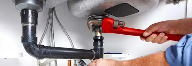 Garbage disposal repair technician tightening the sink drain and disposal connection in Clearwater, FL