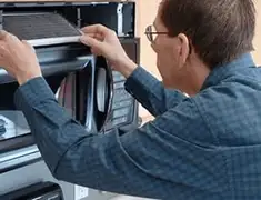 Appliance repair technician replacing a microwave vent filter in Clearwater, FL
