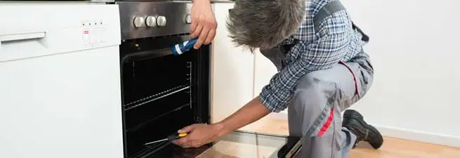 Oven repair technician inspecting and servicing an electric oven in Clearwater, FL