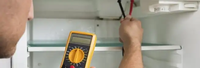 Refrigerator repair technician testing electrical components with a multimeter in Clearwater, FL