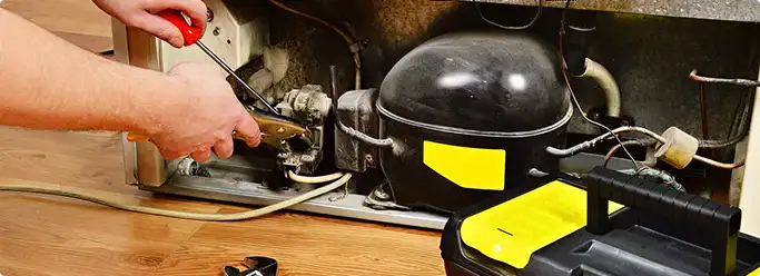 Refrigerator repair technician fixing the compressor and wiring in Clearwater, FL
