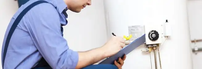 Water heater repair technician inspecting the unit and recording service notes in Clearwater, FL